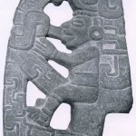 „Hacha“ (Axt) enthält eine menschliche Figur, umgeben von einem im Tajin-Stil typischen Ornament Grau-grüner Stein. Fundort unbekannt. Kultur der mittleren Golfküste, Tajin-Kultur. Etwa 500-1200. Höhe: 23 cm. Museo Nacional de Antropologia, Mexiko D.F.